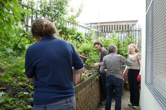 Group of volunteers of various ages work together on a raised bed in a community garden.