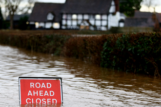 Image of a flooded road with a sign saying "Road ahead closed"