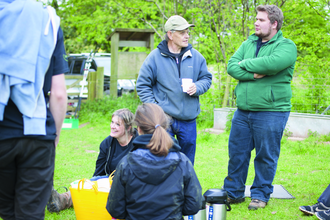 Gathering of people in front of a green garden.