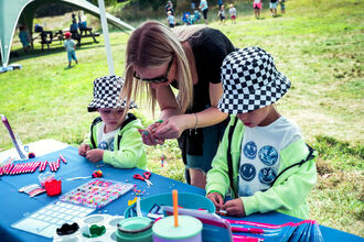An adult instructing two young people in a craft activity