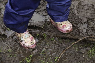 A pair of wellies standing on muddy soil