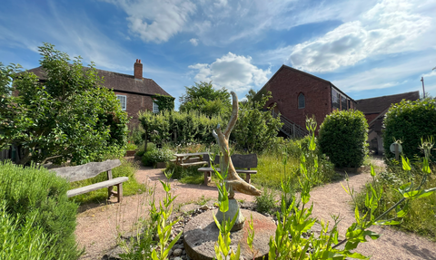 Pretty garden and otter water sculpture infront of old country buildings