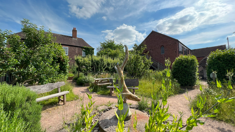 Pretty garden and otter water sculpture infront of old country buildings