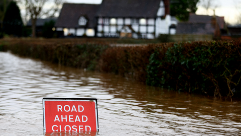 Image of a flooded road with a sign saying "Road ahead closed"