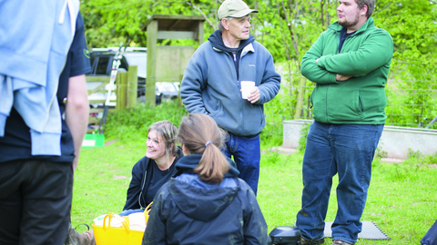 Gathering of people in front of a green garden.