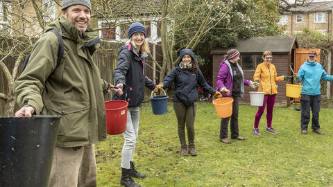 Group of smiling people holding buckets between each other.