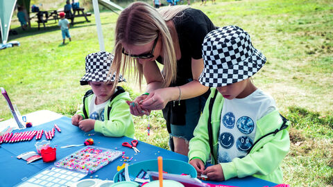 An adult instructing two young people in a craft activity