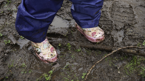A pair of wellies standing on muddy soil