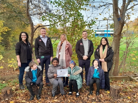 Group of school children and adults posing for photo in woodland